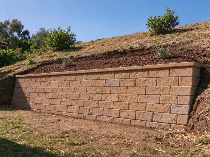 The same slope held by a new segmental block retaining wall with a cap and planted backfill
