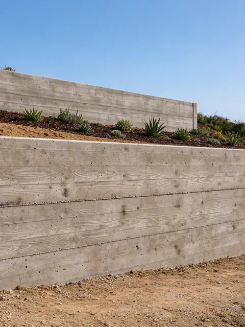 Two low board-formed concrete garden walls terracing a sloped coastal lot in Solana Beach
